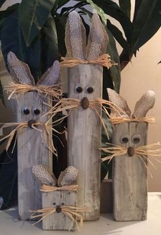 three wooden logs with eyes and ears made to look like rabbits