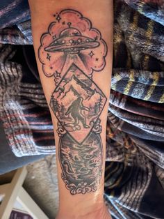 a tattoo on the arm of a woman with an alien spaceship above her head and mountains