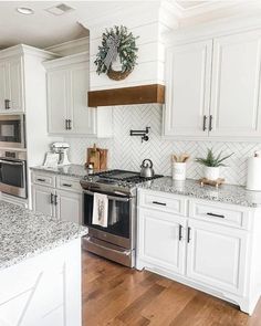 a kitchen with white cabinets and marble counter tops, stainless steel appliances and wooden floors