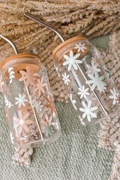 two glass vases with flowers painted on them are sitting on a rug next to a piece of wood