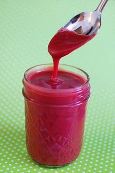 a spoon is pouring ketchup into a jar