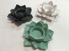 three ceramic flowers sitting on top of a table