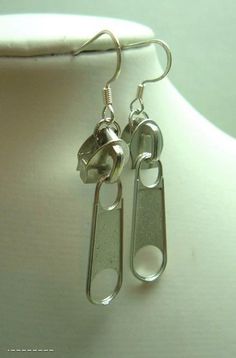 two pairs of silver colored metal earrings on a mannequin's neckline