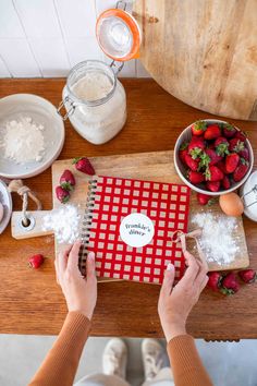 a person cutting strawberries on top of a wooden table