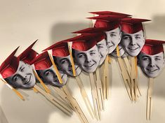 a group of people wearing graduation hats and holding toothpicks with faces on them