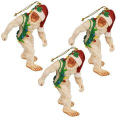 three christmas ornaments are hanging from strings on a white background, one is wearing a santa hat and the other has a green scarf around his neck