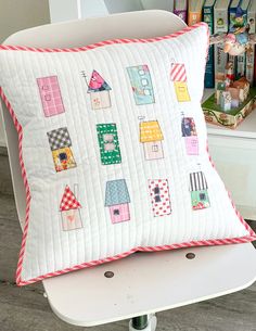 a white chair with a quilted pillow on it's back in front of a shelf