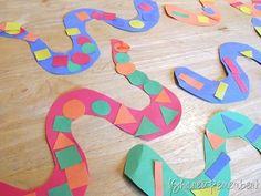 colorful snake cut out from paper on a wooden table with scissors and tape to make them look like snakes