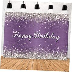 a purple and white birthday card with sparkles on the wall, in front of a wooden floor