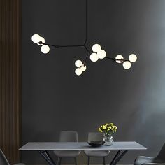 a dining room table and chairs with lights hanging from it's ceiling above them