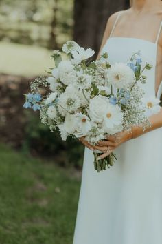 a woman holding a bouquet of white and blue flowers