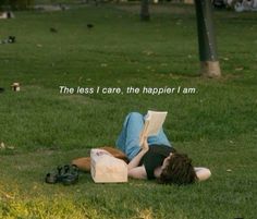 a woman laying on the grass reading a book