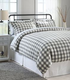 a bed with white and black checkered comforter in a bedroom next to a window