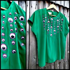 a green shirt with eyeballs on it is hanging up against a wooden fence and another photo has been taken