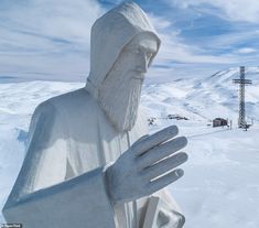 a statue of a man holding a tray in the snow with a ski lift in the background