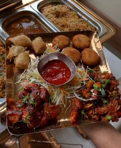 several trays filled with different types of food and dipping sauce on top of them