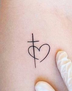 a woman's stomach with a cross and heart tattoo on it