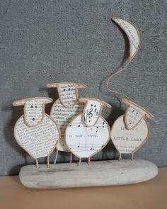 three wooden sheep with musical notes on their backs, sitting on a table next to a gray wall