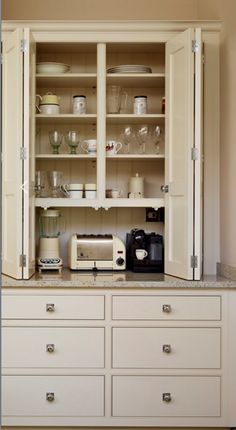 an open cabinet with many dishes and cups on it's shelves in a kitchen