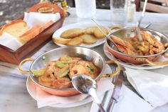 two pans filled with food sitting on top of a table next to some bread