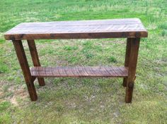 a wooden table sitting on top of a grass covered field next to a green field