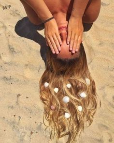 a woman with her hands on top of her head in the sand