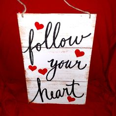 a wooden sign that says follow your heart with hearts painted on the front and bottom