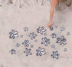 a person standing in the sand next to blue and white flower shaped glass magnets