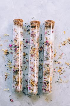 three glass tubes filled with flowers on top of a white surface next to each other