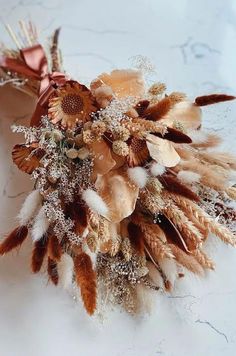 an arrangement of dried flowers and feathers on a table