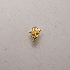 a gold colored brooch with green and pink flowers on it's back side