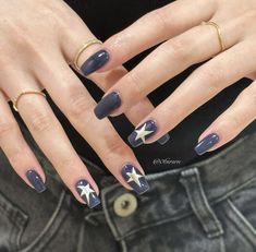 a woman's hands with blue and white manicures on their nails, holding her hand out to the camera