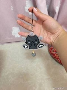 a hand holding a black and white keychain with an animal charm hanging from it's side