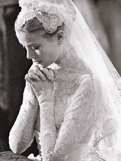 a black and white photo of a woman in a wedding dress looking down at her hands