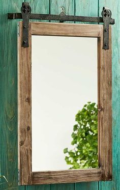 a mirror hanging on the side of a wooden wall next to a potted plant