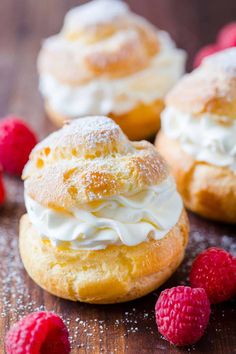 some raspberries are on a wooden table and one is frosted with icing