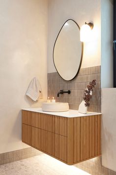 a bathroom with two sinks and a large round mirror above the sink is lit by lights