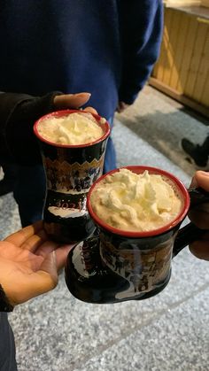 three people holding two mugs filled with food