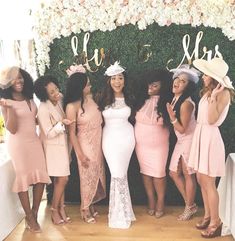 a group of women standing next to each other in front of a flower covered wall