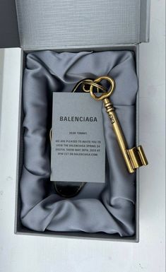 an open box with a golden key in it that says baleinciaga on the front