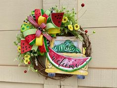 a watermelon welcome wreath hanging on the side of a house