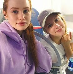 two young women sitting next to each other on an airplane