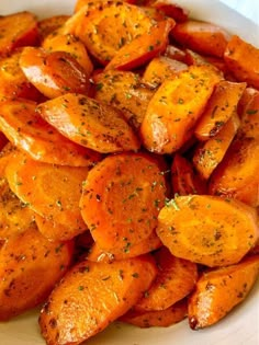 a white plate topped with cooked carrots covered in seasoning