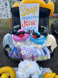 a car trunk filled with stuffed animals and a sign that says soap can help jesus clean the soul