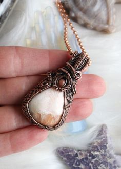 Embark on a journey of tranquility with our Peach Scolecite Copper Wire Wrapped Necklace—a masterpiece of intricately woven copper embracing a teardrop-shaped peach scolecite. This ethereal creation, adorned with a pink jasper in the bail, radiates strength and feminine energy. Peach scolecite, known for its calming properties, is delicately encased in copper, creating a harmonious fusion of beauty and high vibrational energy. Embrace the gentle vibrations and soothing aura of this handcrafted n Elegant Wire Wrapped Copper Necklace, Healing Copper Wire Wrapped Crystal Necklace, Unique Wire Wrapped Copper Crystal Necklaces, Copper Wire Pendant Necklace With Natural Stones, Pink Jasper, Spiritual Hand-wrapped Copper Wire Necklace, High Vibrational, Vibrational Energy, Wrapped Necklace