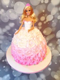 a barbie doll cake with pink and white frosting on the top, sitting on a plate