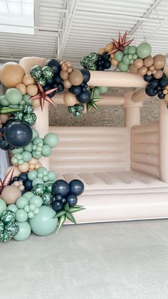 an inflatable arch is decorated with balloons and greenery