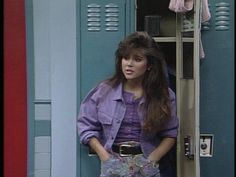 a woman standing in front of a locker with her hand on her hip and looking at the camera