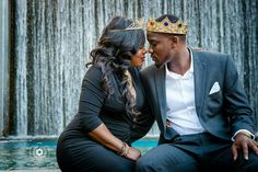 a man and woman sitting in front of a fountain with a crown on their head