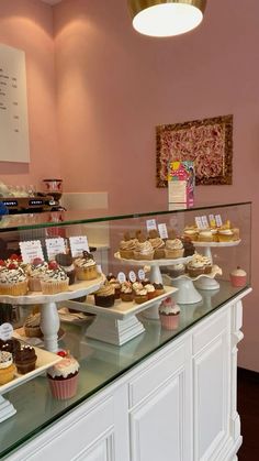 a display case filled with lots of cupcakes on top of white counter tops